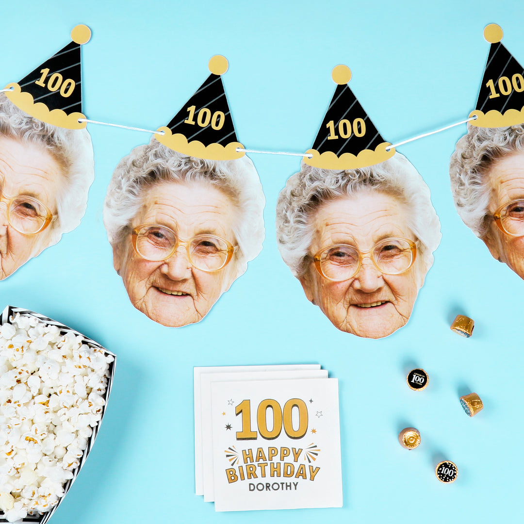 Birthday decorations with an elderly woman's face cutout, popcorn, and a card on a blue background.
