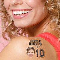 Woman with a temporary tattoo on her shoulder that reads 'Double Digits Bruh 10'.