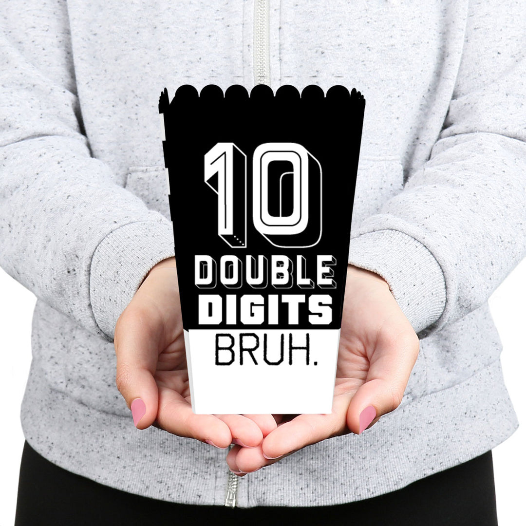 Person holding a black and white popcorn box with '10 Double Digits Bruh.' text.