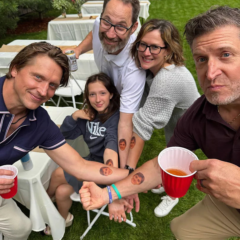 Group of people with red cups and temporary tattoos outdoors