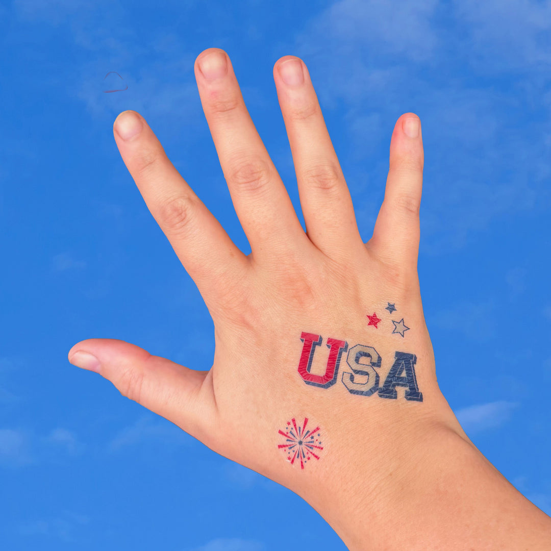 Hand with 'USA' tattoo against a blue sky