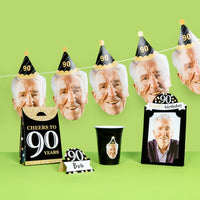 90th birthday party decorations with face masks, cups, and banners on a green background