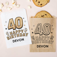 Happy Birthday card and paper bag with '40 Happy Birthday Devon' text on a light pink background with cookies and popcorn.