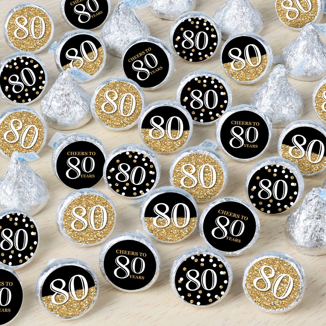 A collection of round candy stickers with gold and black designs, and the number 80 prominently displayed, indicating a celebration for an 80th birthday.