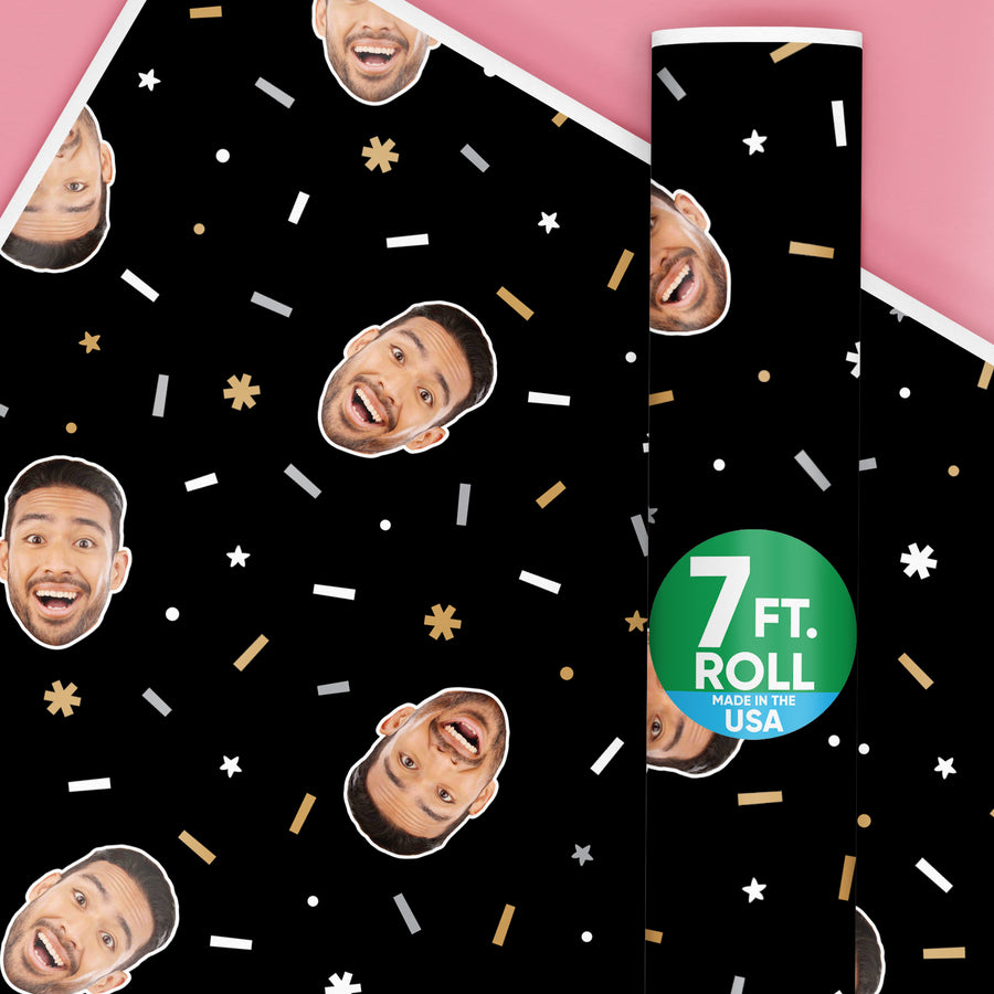 A roll of wrapping paper with a black and gold design, featuring personalized photo uploads and festive confetti patterns. The paper is marked with a 7 ft.