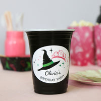 Black party cup with a personalized label for Olivia's birthday party, featuring a witch hat design.