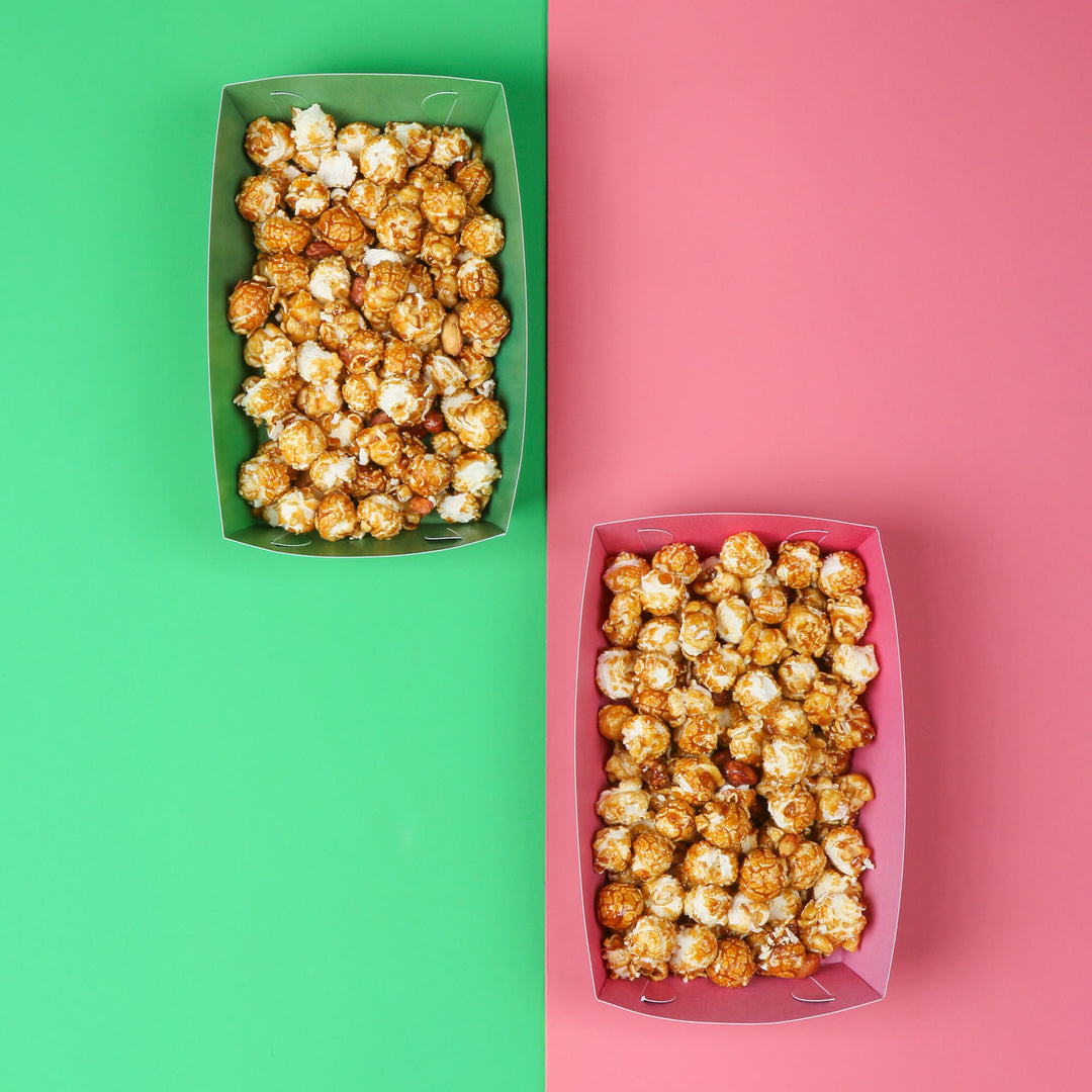 Two containers of popcorn, one green and one pink, on a split green and pink background.