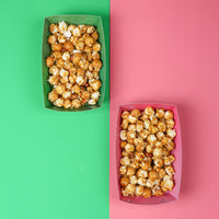 Two containers of popcorn, one green and one pink, on a split green and pink background.
