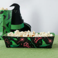 Black halloween popcorn box with colorful designs filled with popcorn, placed on a green surface.