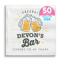 A custom text napkin with 'CHEERS! Devon's Bar CHEERS TO 40 YEARS' printed on it, featuring two clinking beer mugs.