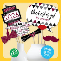 Graduation-themed photo props with 'Class of 2026' and 'The best is yet to come' signs on a yellow background.
