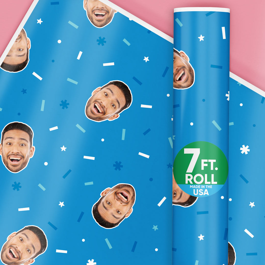 A roll of custom blue wrapping paper with a fun face photo pattern, and a label indicating the paper is 7 ft long, made in the USA.
