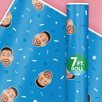 A roll of custom blue wrapping paper with a fun face photo pattern, and a label indicating the paper is 7 ft long, made in the USA.