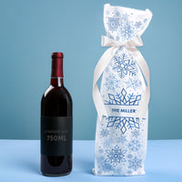 Red wine bottle with a decorative Custom snowflake-patterned gift bag on a blue background