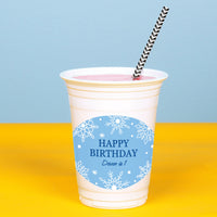 White cup with blue 'Happy Birthday' custom label on a yellow table against a blue background