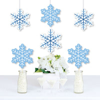 A set of blue snowflake-shaped paper decorations displayed as wall hangings and centerpieces at a winter holiday party.
