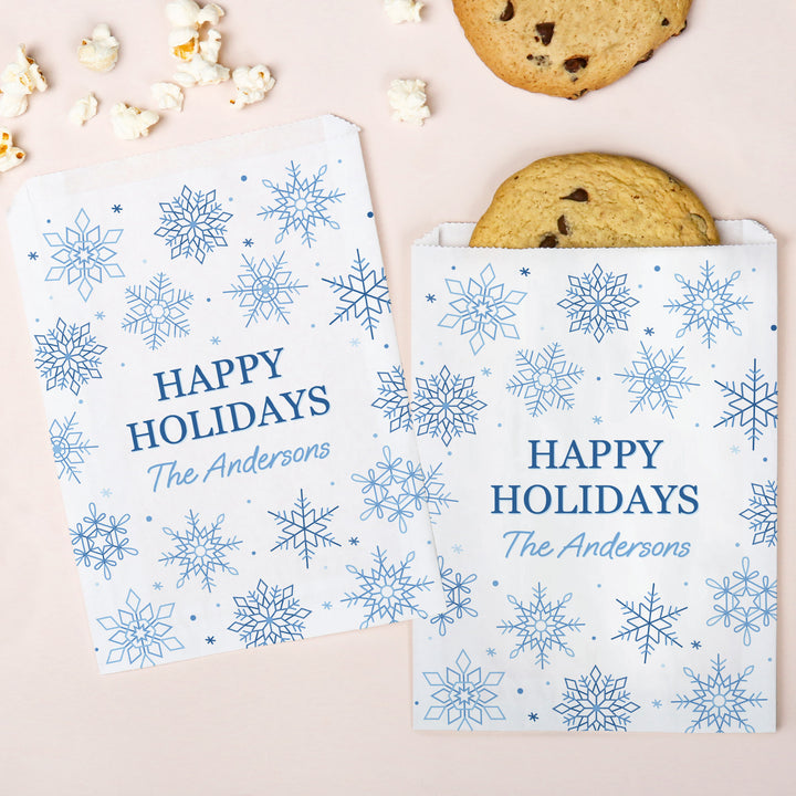 Custom cookie bags with snowflake pattern and 'Happy Holidays The Andersons' text, surrounded by cookies and popcorn.