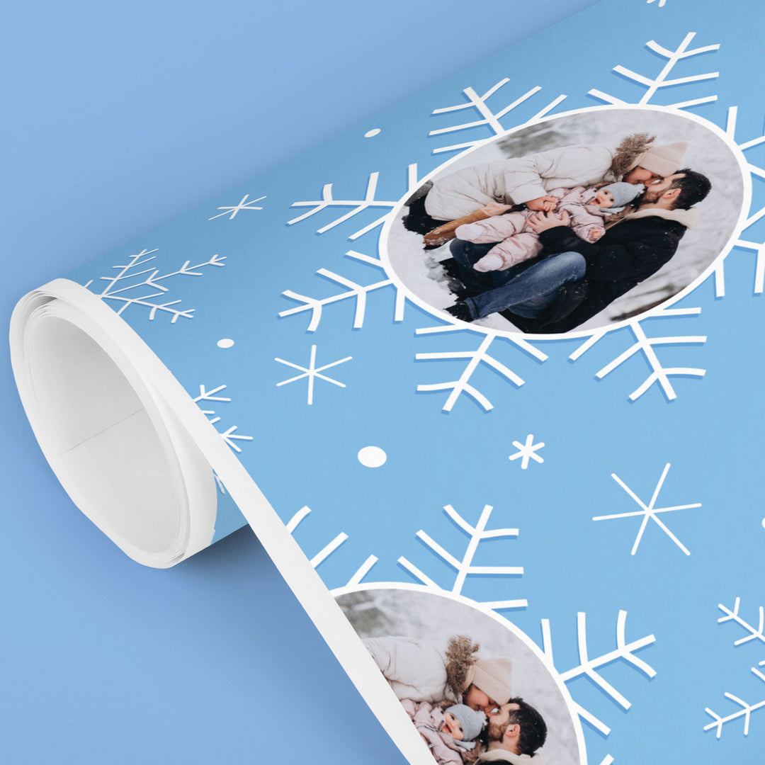Roll of blue wrapping paper with white snowflake pattern and photo insert.