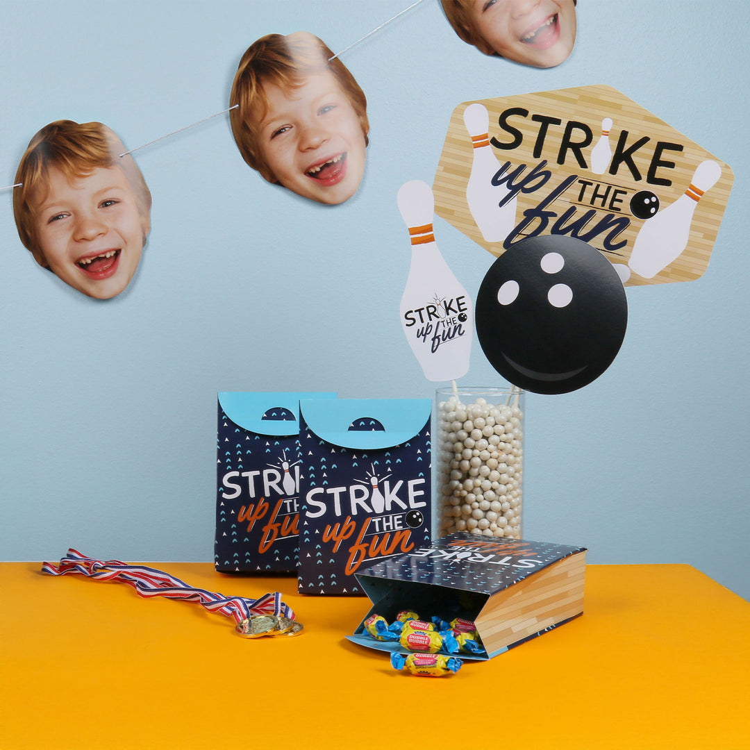 Bowling-themed party decorations with cutout faces, bowling pins, and a ball on a blue and orange background.