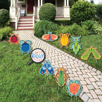 A set of colorful lawn decorations featuring various insects displayed on a grassy area leading up to a house entrance.