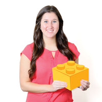 Woman holding a large yellow toy block sign against a white background