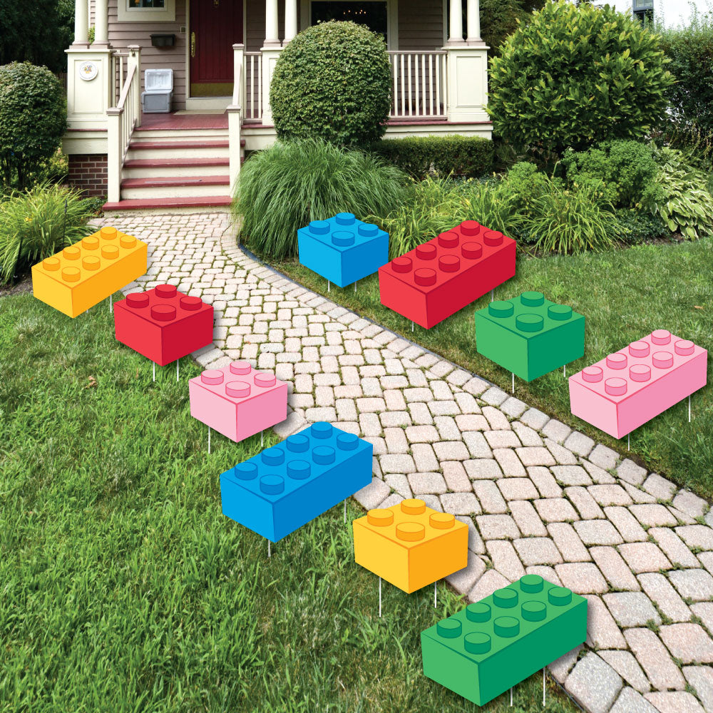 Large Colorful toy building blocks yard signs arranged on a lawn in front of a house.