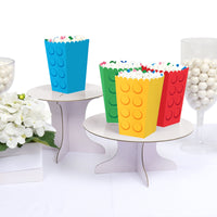 Colorful lego-style popcorn buckets on a white surface with decorative elements.