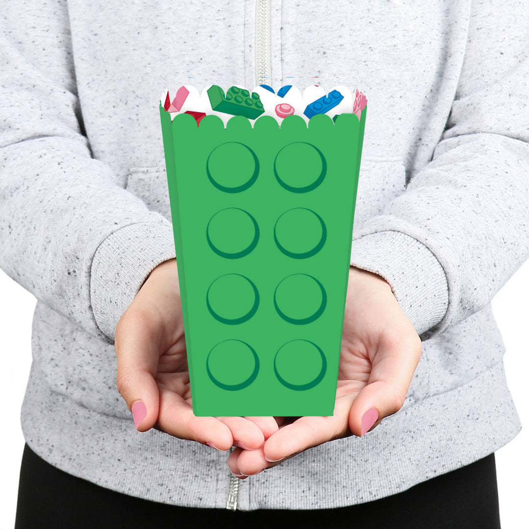 Person holding a green paper bag with colorful handles against a gray background