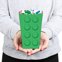 Person holding a green paper bag with colorful handles against a gray background