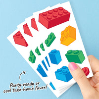 Sheet of colorful building block party favor tattoos held by a hand on a blue background