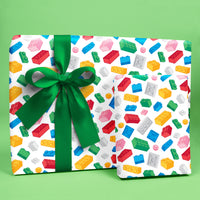 Gift box with colorful LEGO pattern and green ribbon on a green background