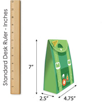 Green paper bag with buckle details next to a ruler for size measurement on a white background