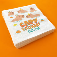 Stack of birthday-themed napkins with cartoon hippos and personalized text on an orange background