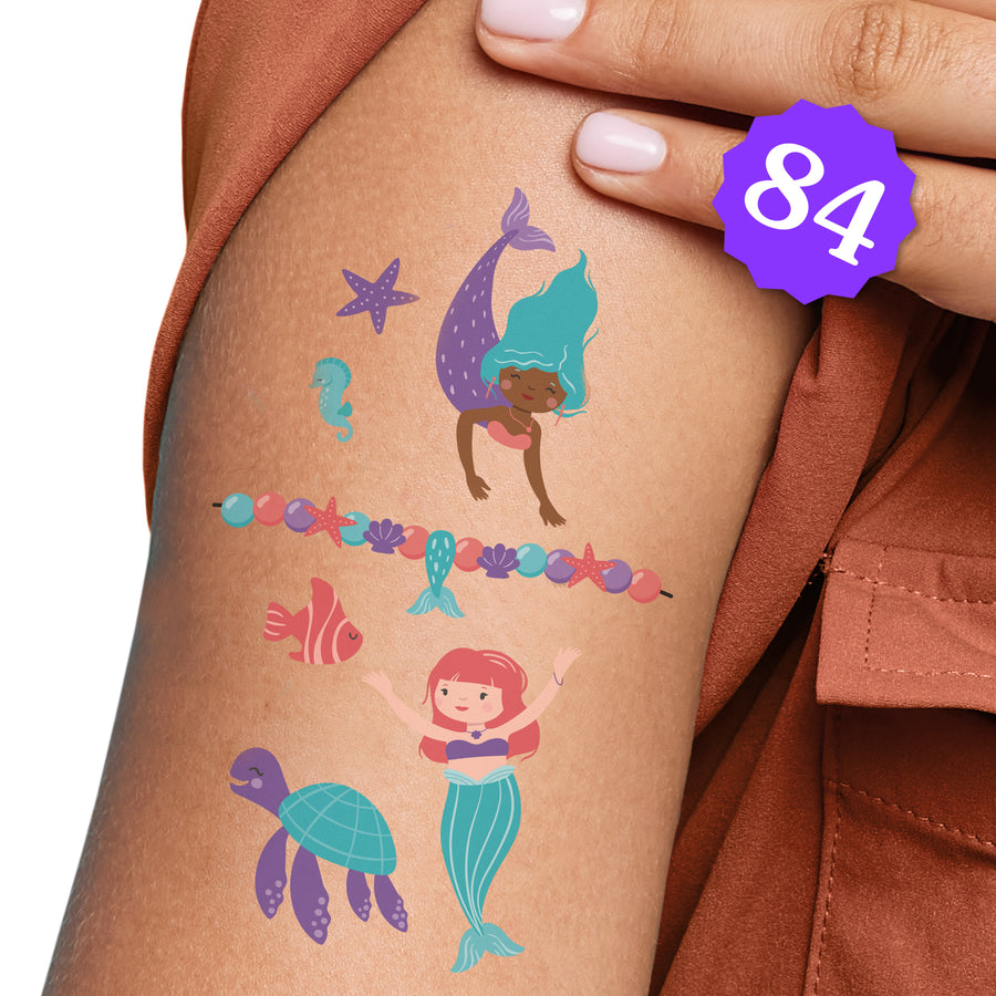 A person's arm showcasing a series of colorful mermaid-themed temporary tattoos, with a count of 84 tattoos displayed.