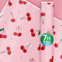 Rolls of wrapping paper with a pattern of red cherries and pink bows on a pink background, indicating a 7 ft. roll made in the USA.