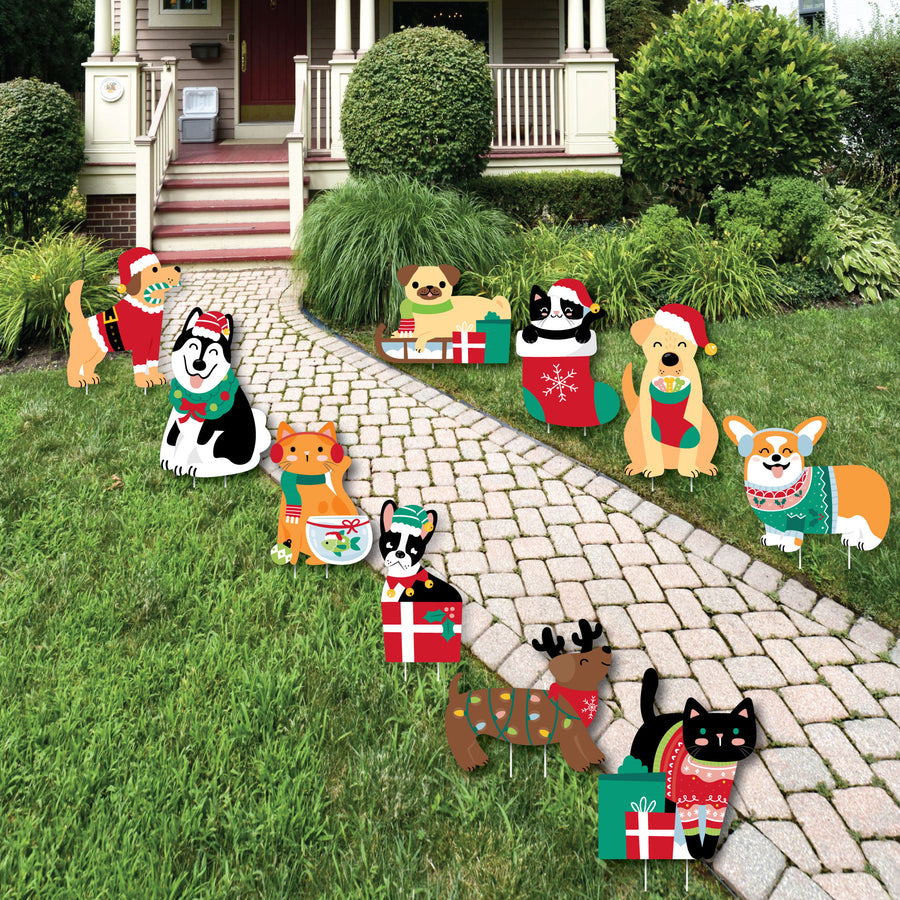 A set of Christmas-themed lawn decorations featuring various cartoon pets with holiday accessories displayed on a grassy area leading up to a house entrance.
