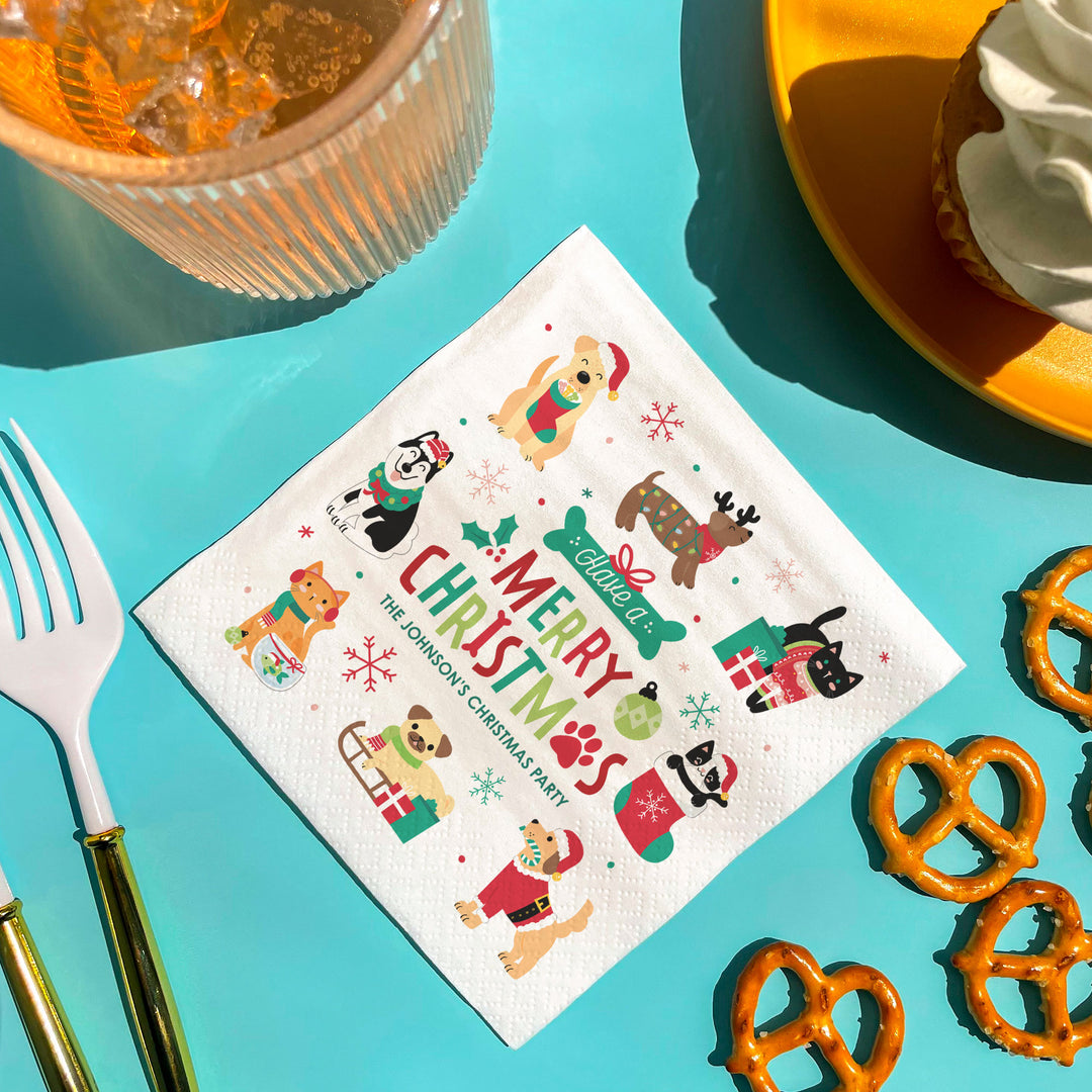 Napkin with Christmas-themed pets designs on a turquoise surface with food items.