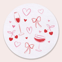 Round coaster with red wine glasses, hearts, and bows on a white background