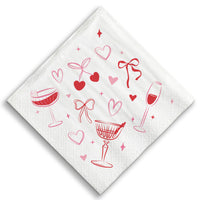 White napkin with red wine glass, heart, and bow designs on a white background