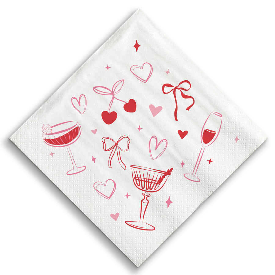 White napkin with red wine glass, heart, and bow designs on a white background