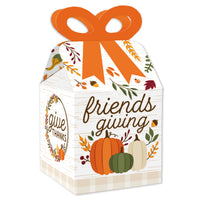 A square favor gift box with a bow-shaped top, decorated with fall-themed patterns and the text 'friendsgiving'. It has a white background with orange, green, and beige colors and is closed with a ribbon.