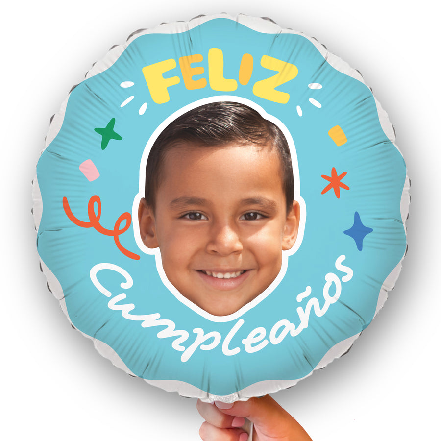 A personalized 'Feliz Cumpleanos' balloon with a face photo and birthday greetings printed on it, held by a hand.