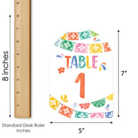 Colorful table number with decorative elements and a ruler for scale on a white background