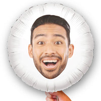 A custom round white balloon with a double-sided print of a person's face, held in a hand.