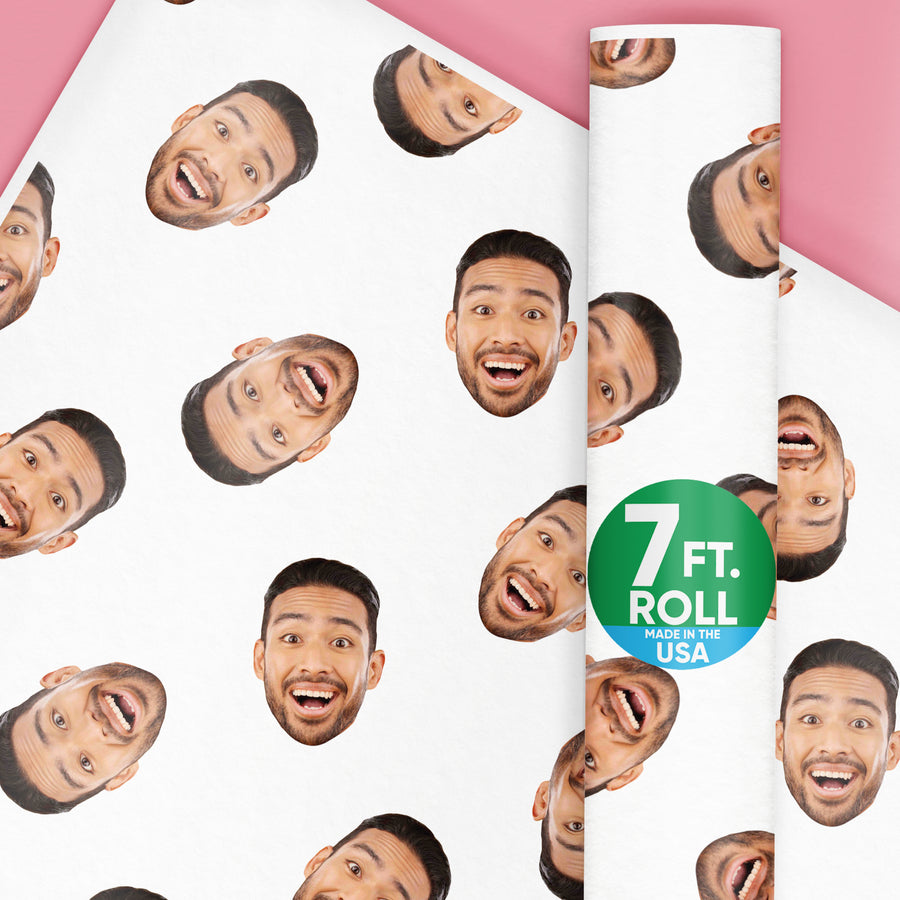 A roll of custom wrapping paper with multiple photos of a person's face printed on it, with a label indicating the paper is 7 feet long and made in the USA.