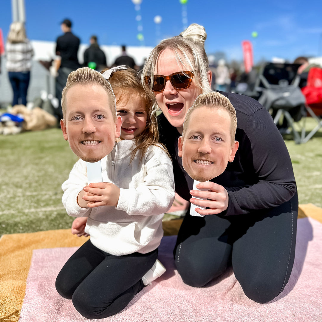 Family with cardboard cutout heads at an outdoor event