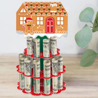 A DIY gingerbread house cash holder gift in a red and green 2-tier cake shape with slots holding rolled-up bills, designed for a Christmas or holiday party.