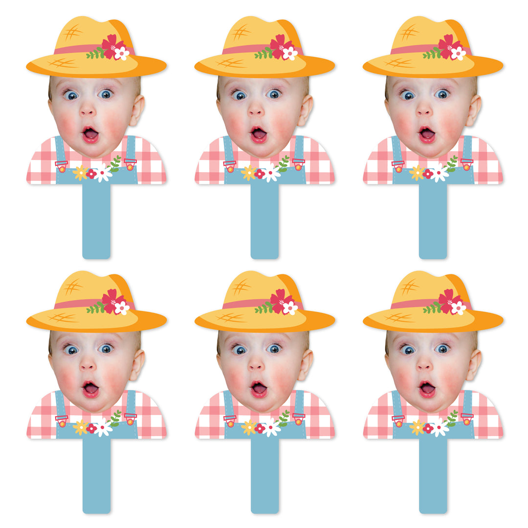 A set of six face cut-out paddles with a photo of a girl in a farmyard setting, wearing a yellow hat with flowers on it, designed for use as party props.