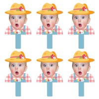 A set of six face cut-out paddles with a photo of a girl in a farmyard setting, wearing a yellow hat with flowers on it, designed for use as party props.