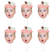 A set of six face cut-out paddles designed for photo booth props, with a pumpkin theme, featuring the same photo of a girl's face in each.